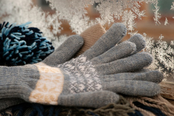 Gloves on the background of a frosty window. Warm gloves on the windowsill against the background of ice crystals on the window glass. Clothes for a cold winter.