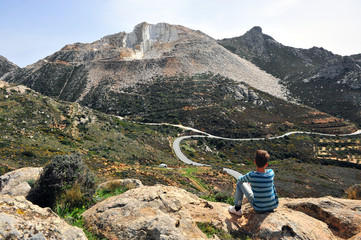 Boy looking at winding road in mountains - obrazy, fototapety, plakaty