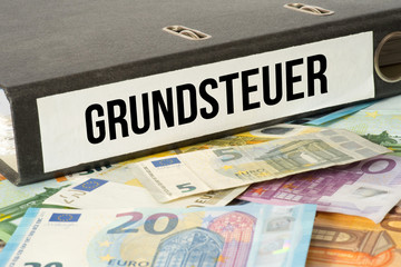 Euro Geldscheine und ein Ordner mit dem Grundsteuer Unterlagen