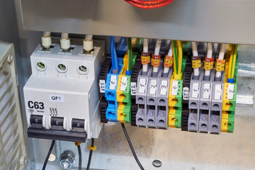 Modular circuit breaker and a number of terminals in the electrical Cabinet. Electrical wires or cables are connected to the switch and terminals. Reliable and modern power distribution.
