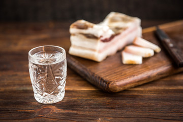 Vodka and salt pork fat on dark wooden background. Traditional Ukrainian and Russian appetizer when dining. Food when drinking alcohol.
