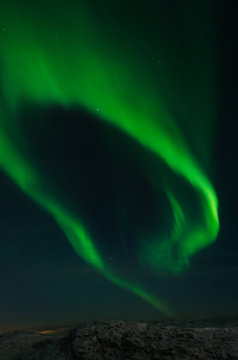 Northern lights, aurora in the night sky above the snowy hills.