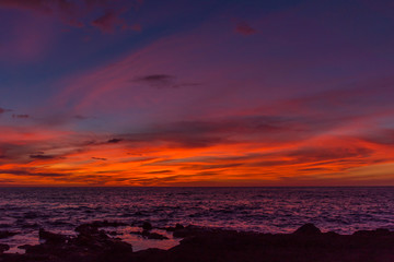 Tropical orange sunset over ocean with new moon