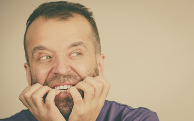 Scared adult man biting nails
