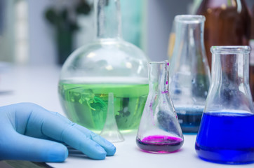 Table full of chemicals and flasks. Chemical lab. Hands
