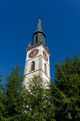 Fototapeta premium Close-up of the bell tower of Saint Jacob cathedral church kirche in Cham town (Zug, Switzerland) on the clear blue sky background on a summer day
