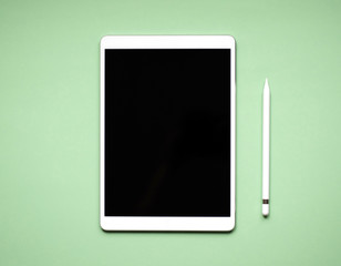 White tablet lying on solid color background.