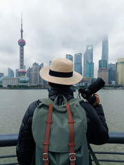 Obraz premium Vertical image of a man traveler with holding camera is looking at View of Shanghai city skyline in the morning.