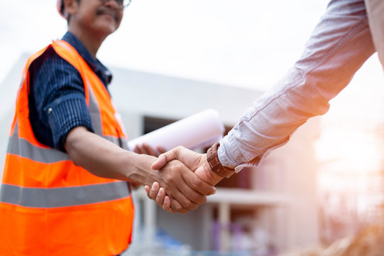 Engineer man handshake with asian business after finishing up meeting, partnership, teamwork, community, connection industriall and investment concept