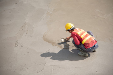 Construction worker wear standard safety uniform pouring and leveling fresh concrete at...