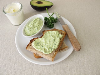 Guacamole mit Avocado, Frischkäse und Petersilie auf einer Scheibe Brot