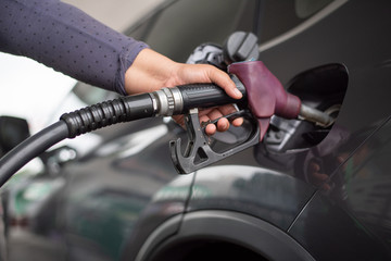 Pumping equipment gas at gas station. Close up of a hand holding fuel nozzle