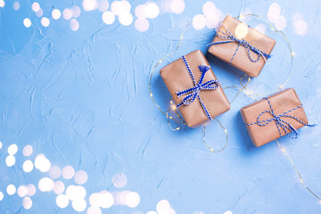 Wrapped boxes with presents  and silver fairy lights on blue textured background.