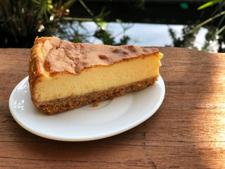New York  cheese cake in white dish on the wooden table with sunlight . Homemade bakery.