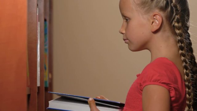 six year old girl standing with books and smiling