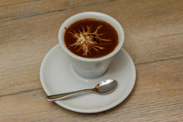 White cup of coffee on wooden table with spoon