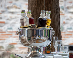Cooling bottles with alcohol on the table set for dinner. The cooler reflects tables and chairs. Greece