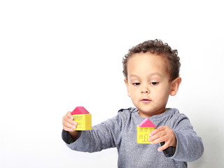 Little boy playing with miniature toy block houses representing property purchase
