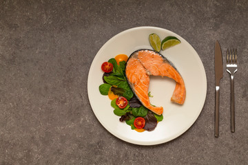 Salmon steak dinner with herbs and tomatoes.
