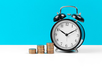 Alarm clock and money coins on the table.