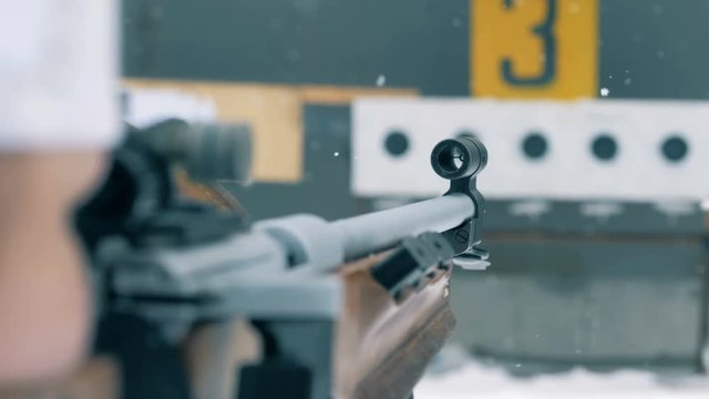 Snowfall and close up of rifle's barrel during aiming process