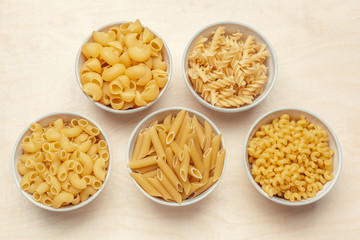 Different pasta types in bowls on the table.