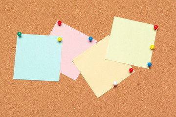 Sticky note pinned on cork board with thumbtacks