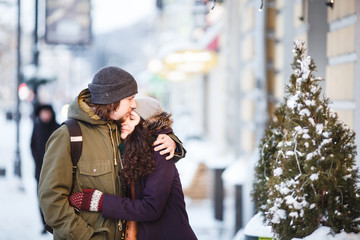 Young couple kissing on the street under the snowfall