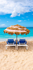 Two chairs and umbrella on the tropical beach of Mullet Bay, Sint Maarten, Caribbean. 
