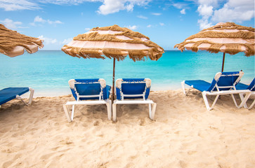 Beach chairs and umbrella on a white sandy beach in Sint Maarten, the Caribbean. Summer vacation concept.