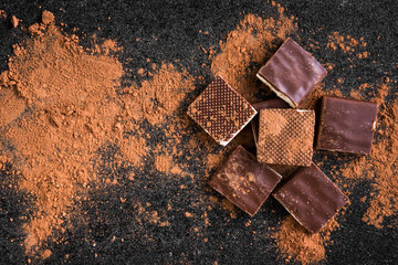 Milk chocolate bar chocolate chips and cocoa on black background