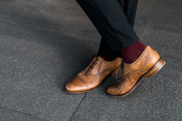 cropped view of male crossed legs in burgundy socks and oxford shoes