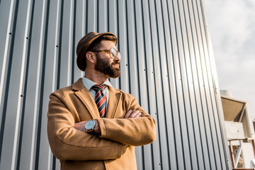 low angle view of businessman standing with arms crossed near metal construction