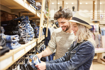 Junges Paar beim Shopping vor der Jeans Auswahl