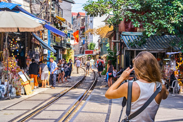 Woman is making a picture of Hanoi city railway Perspective view running along narrow street with houses in Vietnam - obrazy, fototapety, plakaty