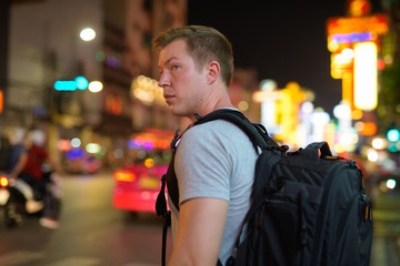 Young tourist man backpacker crossing the streets of Chinatown at night