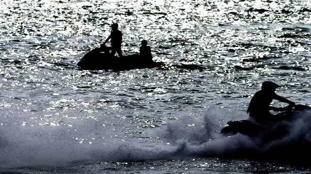 silhouette, a men on a motorbike floats on the sea.