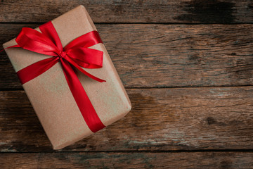 Brown Gift box bow tie Red ribbon On old wood floor top view merry christmas and happy new year concept