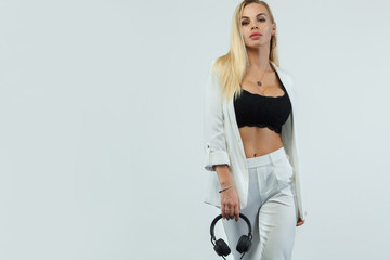 Beautiful sexy blonde DJ woman on white background in studio wearing headphones.