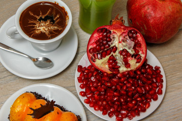 Homemade cake, pomegranate and coffee in a white cup on a wooden vintage table