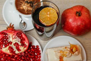 Homemade cake, pomegranate and coffee in a white cup on a wooden vintage table