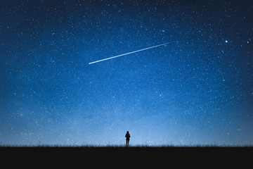 Silhouette of girl standing on mountain and night sky with shooting star. Alone concept. - Powered by Adobe