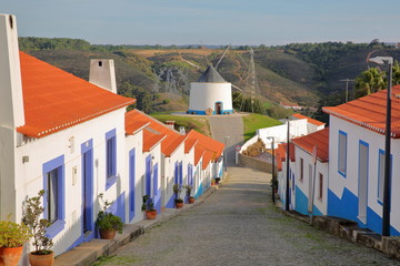 A row of colorful houses along a steep cobbled street inside Odeceixe (near Aljezur), leading to a...