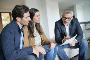   Couple with real-estate agent looking at contract in modern house