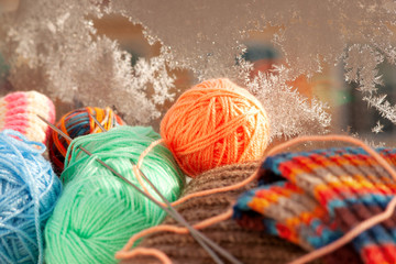 Balls of yarn on the background of a frosty window. Yarn for knitting on a cold winter window-sill...