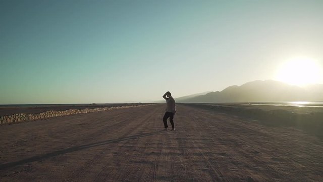 Attractive dancer girl dancing in sandy windy desert at sunny day slow motion