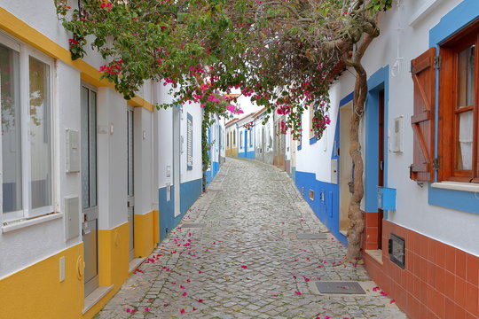 A scenic paved alley with colorful houses and flowers in the fishing village of Ferragudo, Algarve, Portugal