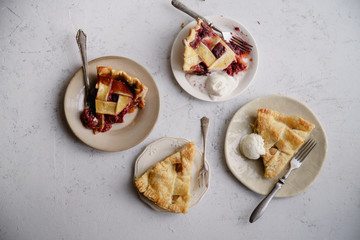 Slices of various pies in little plates. Overhead view, concrete background