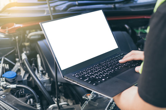 Close up engineer  mechanic using electrnoic diagnostic equipment to tune a car, Laptop blank screen..