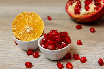 Whole pomegranate, part of pomegranate and pomegranate seeds on wooden table